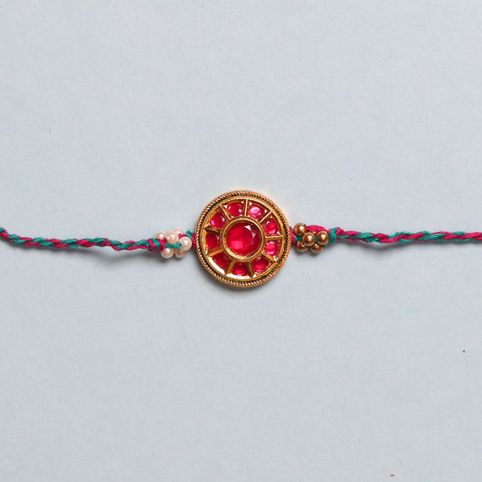 Rakhi bracelet featuring a flower, pearls, and red stone