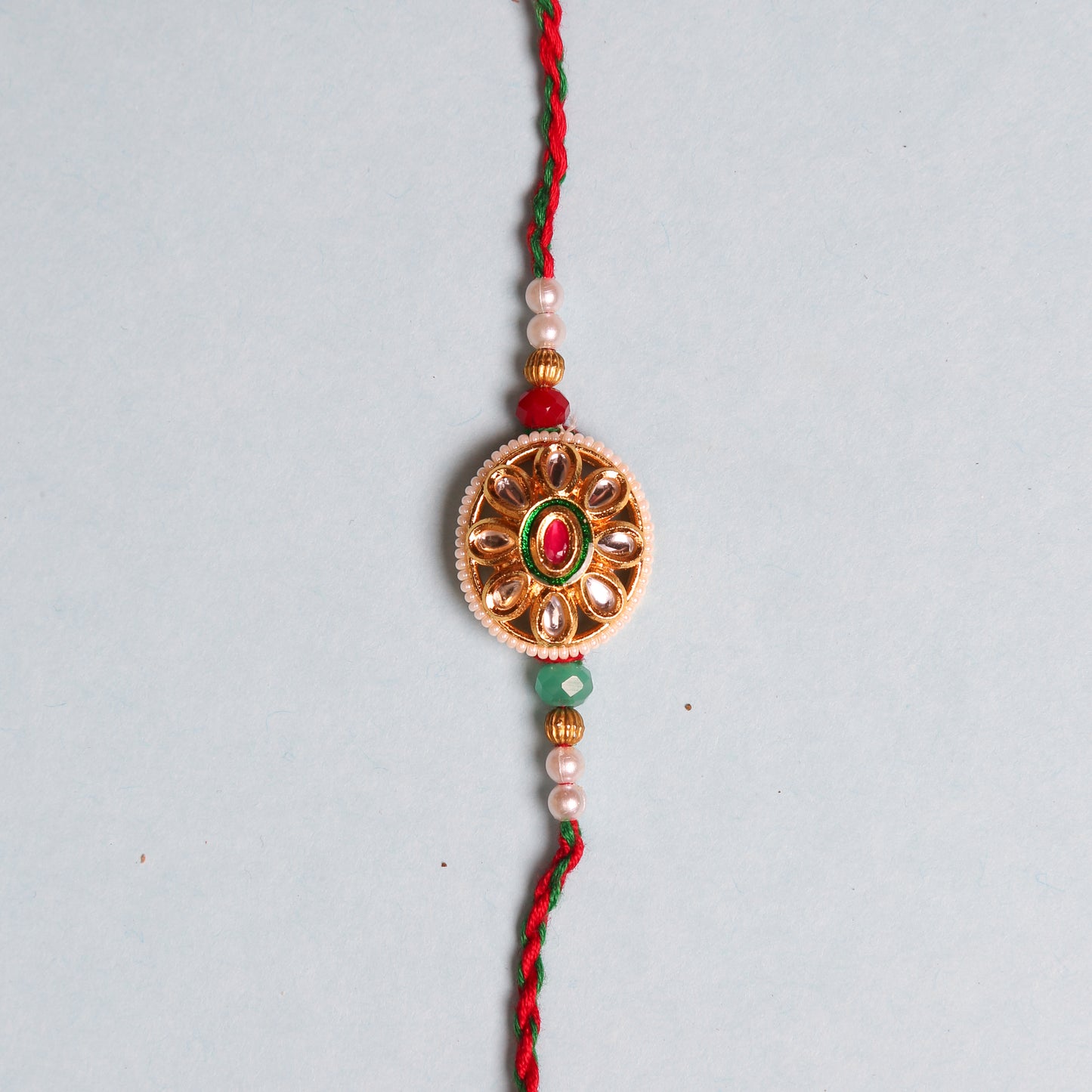 Rakhi with red and green beads, embellished with stones, looks stunning.