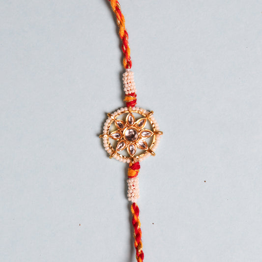 Rakhi bracelet from India featuring pearls and a special stone in wheel design.