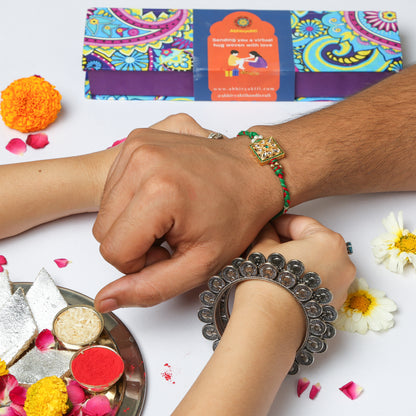 Sister tying a beautiful Green ornate rakhi to her brother and celebrating rakshabandhan in traditional Indian way