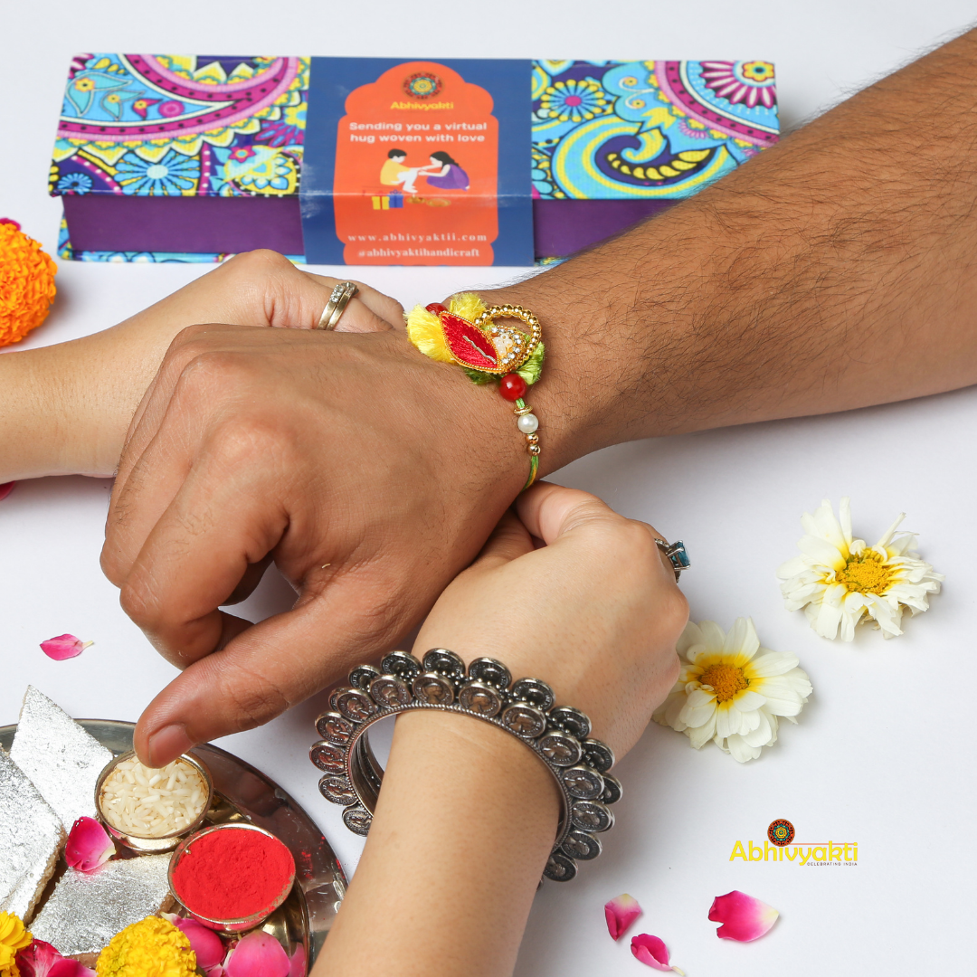 Celebrating rakshabandhan with sister tying beautiful red-yellow zari rakhi to her brother