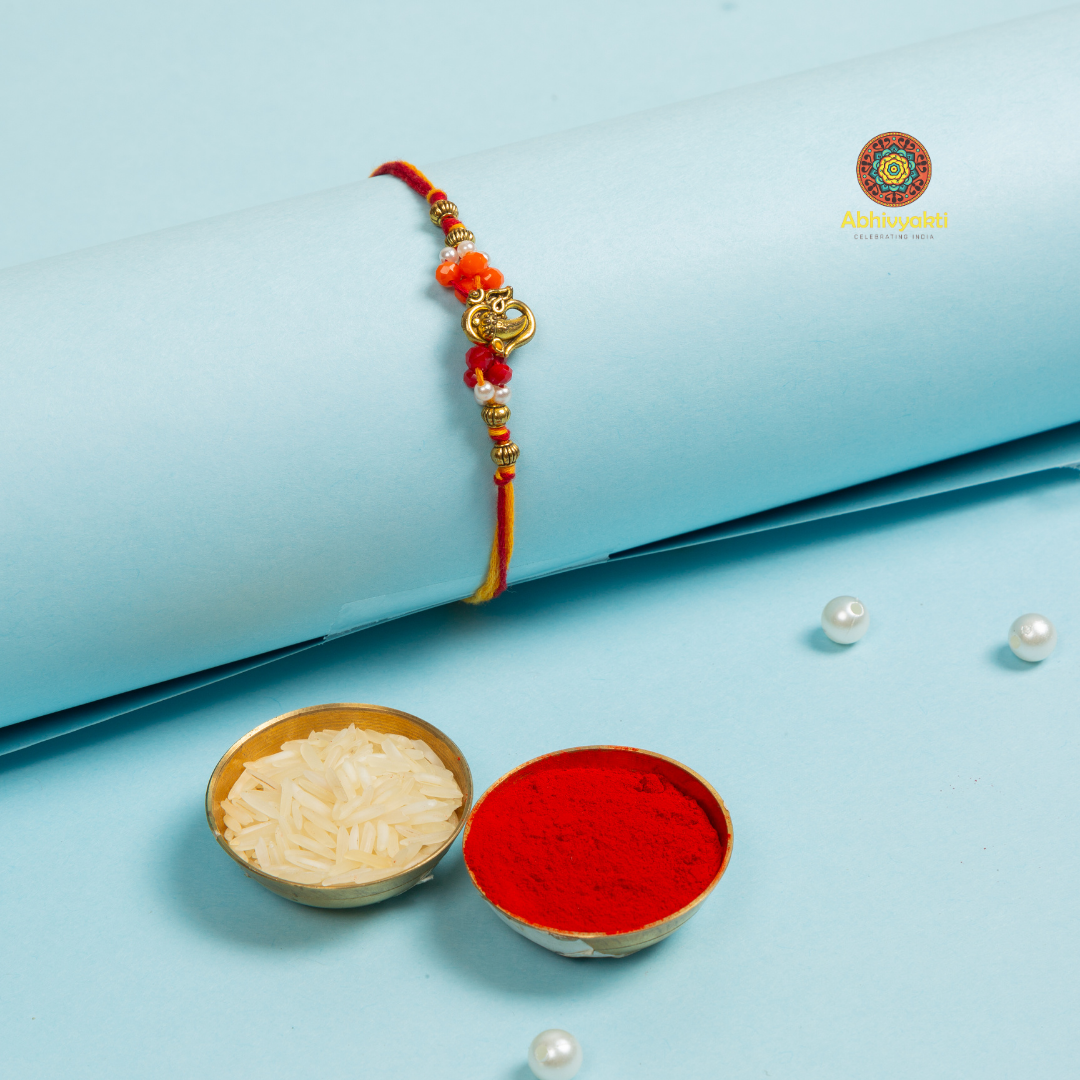 A divine Ganesha Om rakhi with beads, and a small bowl.