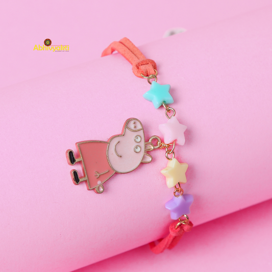 A children's bracelet laid on a pink background, featuring a charm of Peppa Pig in a pink dress and pastel-colored star beads in blue, yellow, pink, and purple. This adorable Peppa Pig rakhi for kids has a coral-colored band.