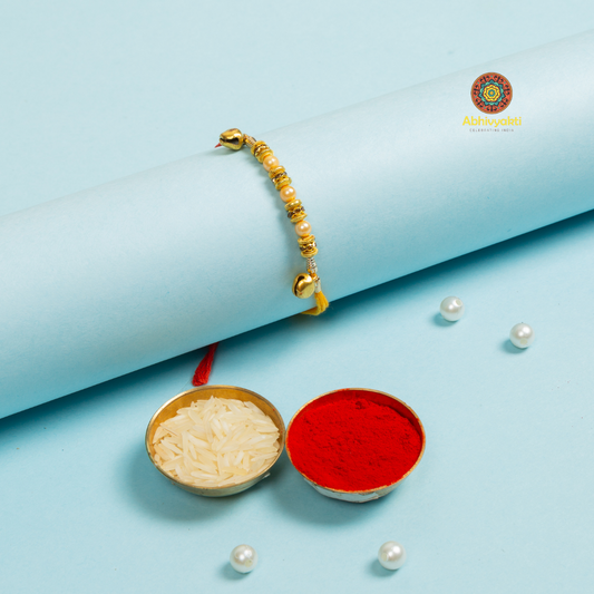 Red and yellow beads arranged in a line on a blue background, thread rakhi with beads and ghungru.