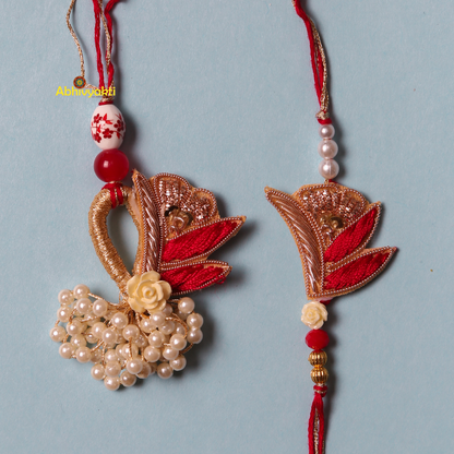 A pair of rakhi lumba in red and white colors adorned with pearls, beads, stones, and a unique design