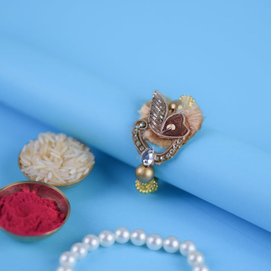Beautiful copper bhaiya zari rakhi with golden beads resting on a blue roll