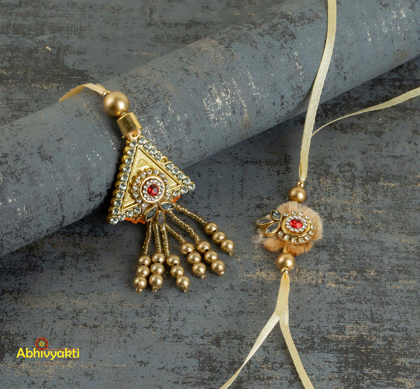 Pair of gold pendants featuring red stones, stone rakhi lumba design with intricate bead and stone details.