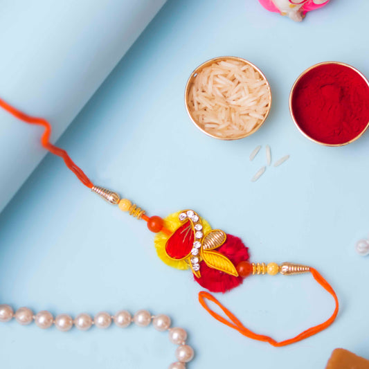 Beautiful Zari rakhi in red and yellow color with roli and rice