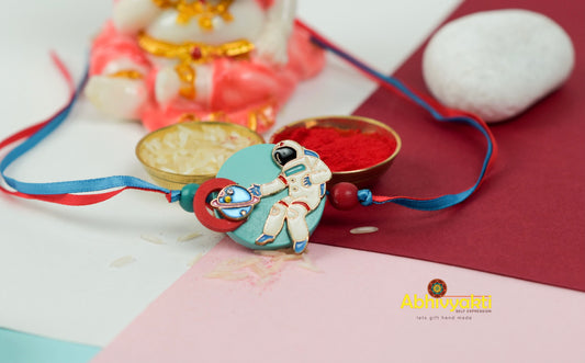 Beautiful kids rakhi adorned with beads and a small figurine with a button.