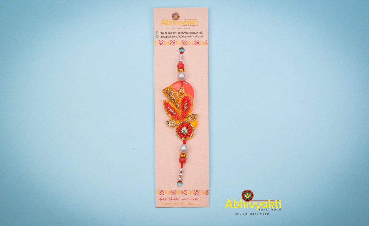 Elegant red and gold rakhi adorned with a gold bead, showcasing a unique zari design with lovely beads and stone.