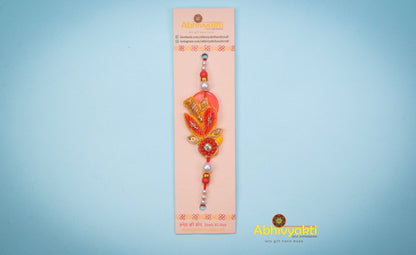 Elegant red and gold rakhi adorned with a gold bead, showcasing a unique zari design with lovely beads and stone.