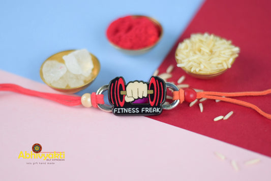 Fitness Kids rakhi adorned with beads, a pin, and a bowl of rice.