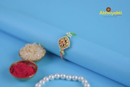  kundan rakhi with pearls and beads on a blue background.