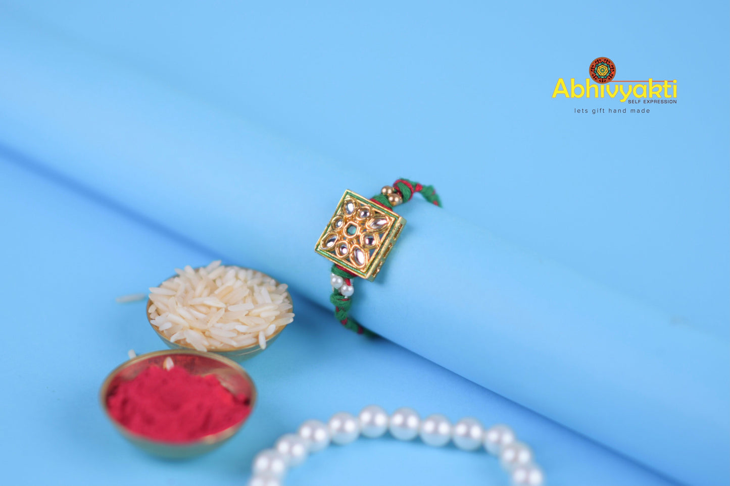 Elegant gold and pearl bracelet adorned with pearls and rice, featuring kundan fancy rakhi with stone and beads