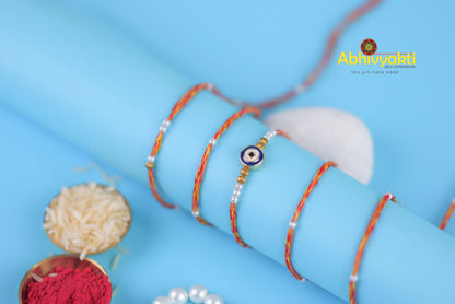 A bracelet adorned with a blue and white evil eye, made of thread with beads.