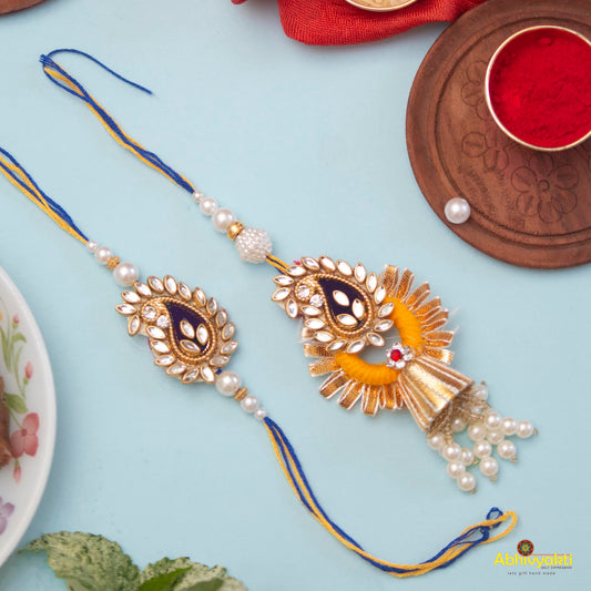 Plate featuring two stunning rakhi lumba embellished with stones and beads, along with a bowl of red and yellow powder.